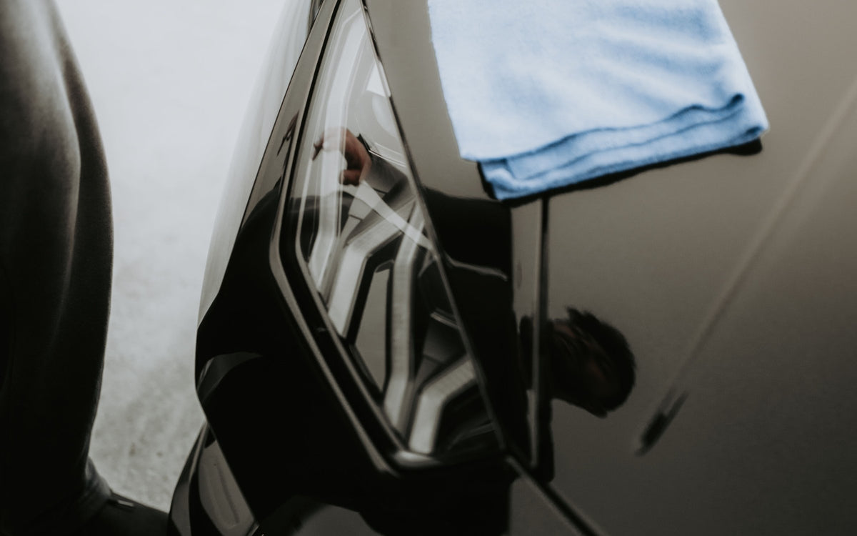 Microfibre cloth resting on a polished black car bonnet (real photo, Pexels / Luke Miller)